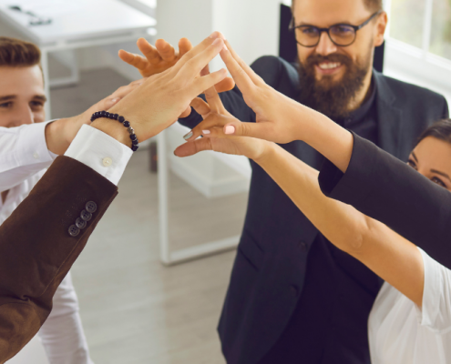 Equipo de trabajo motivado y unido celebrando logros con energía positiva, reflejando el poder de la colaboración y un ambiente laboral saludable.